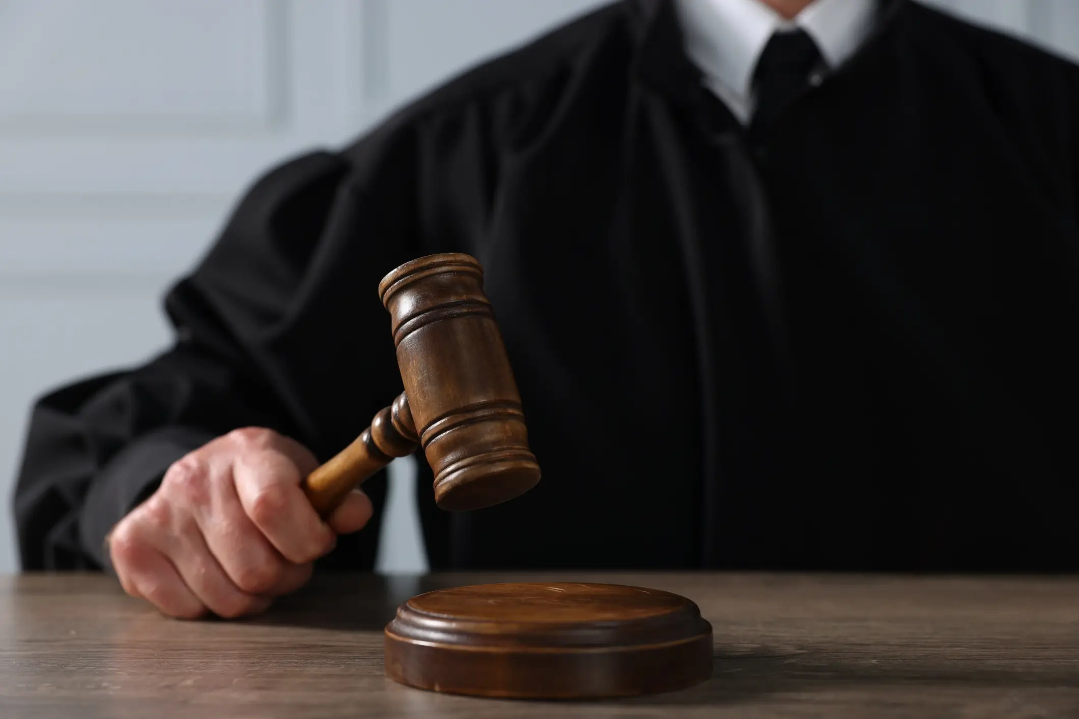 Judge holding gavel over wooden desk.