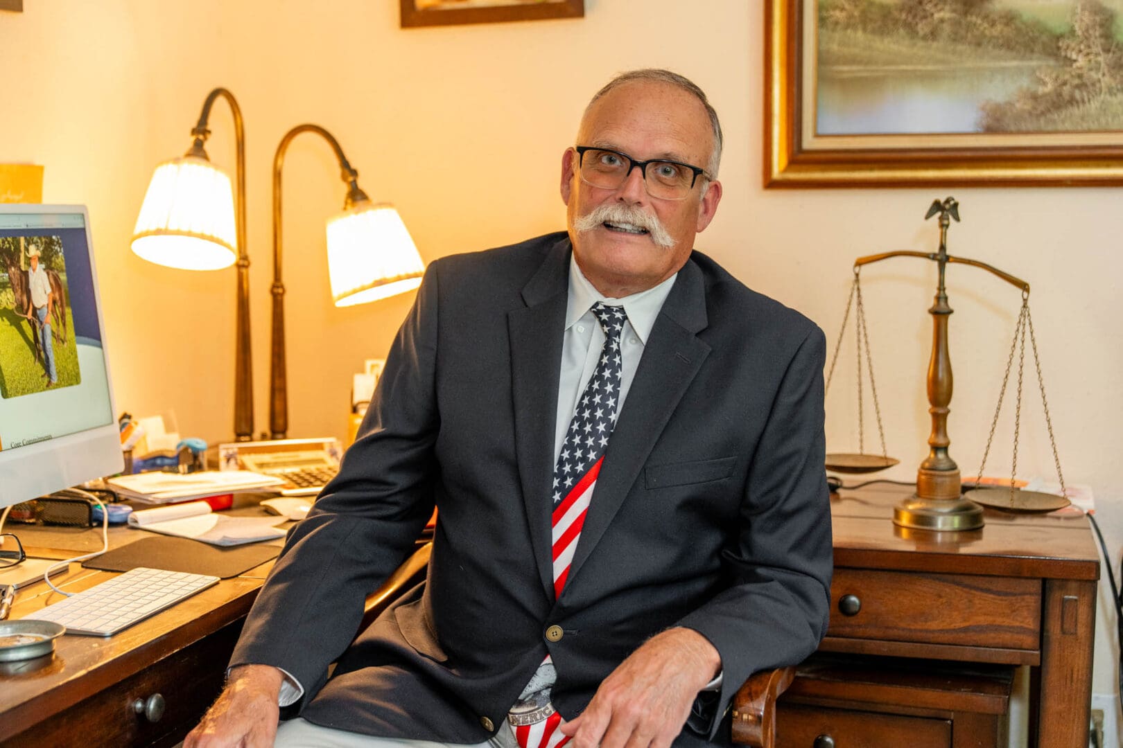 A distinguished man in a suit sitting in a warmly lit office.